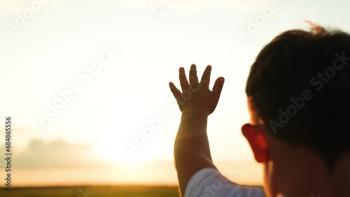 Children dream hopes, Children prayer. Reach out your hands to sky Little girl stretches his hand to sky, dreams in sun nature. Child is playing. Hand of child boy stretches to beautiful sky, sunset