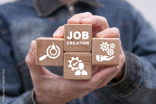Man holding wooden cubes with icons sees inscription: JOB CREATION. Job creation and stability business concept. Employment. photo