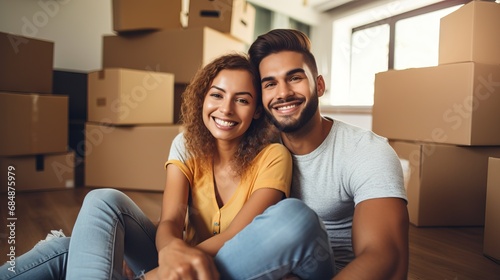 Newly moved-in couple sitting on the floor surrounded by boxes, taking a selfie. photo