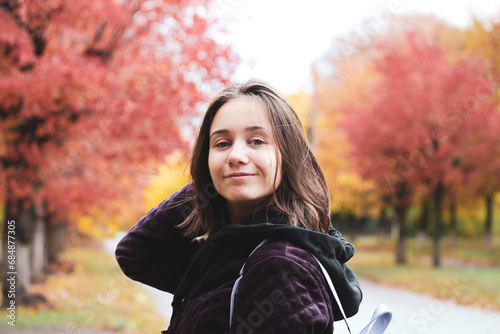 Self confident school girl on a street. Red trees in fall season Young woman portrait outdoors in autumnal day. People on nature in October. Teens on the holidays. University campus, travel lifestyle.