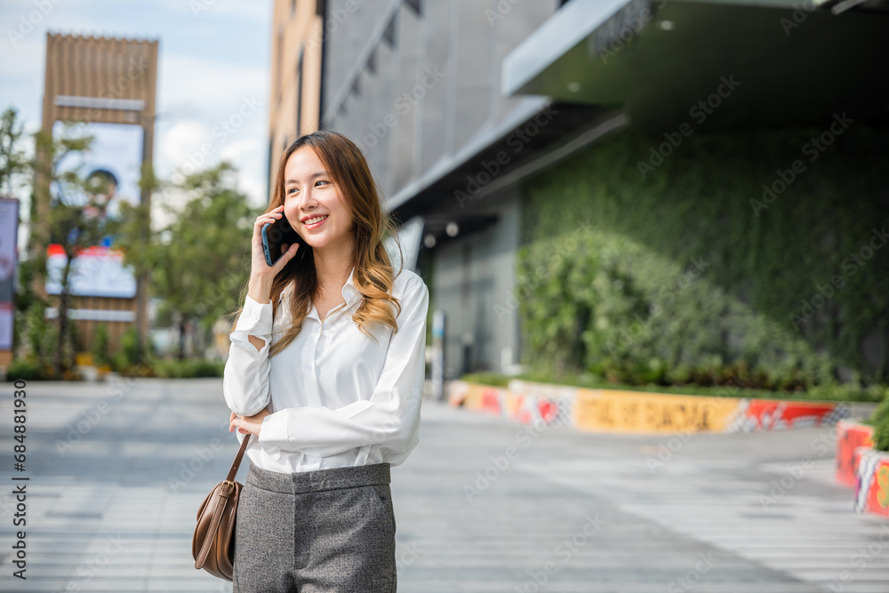 Beautiful young Asian woman calling and talks on telephone or mobile phone in city, Portrait of businesswoman smiling talking on mobile phone, people and technology communication concept Beautiful young Asian woman calling and talks on telephone or mobile phone in city, Portrait of businesswoman smiling talking on mobile phone, people and technology communication concept