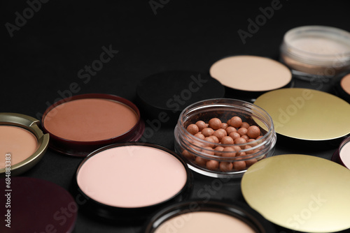 Different face powders on black background, closeup