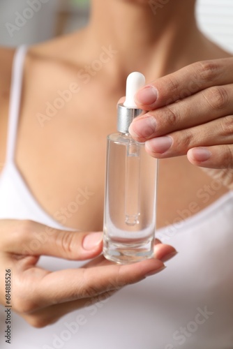 Woman with bottle of cosmetic serum  closeup