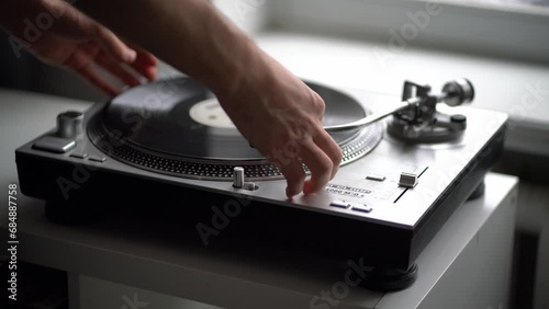 a close up person's hand put the needle on a record, playing vinyl disc at the party photo