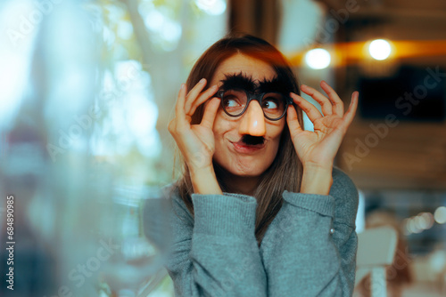 Funny Woman Wearing Silly Mustache Party Accessories Glasses. Girl with a sense of humor using disguise eyeglasses for a prank
 photo