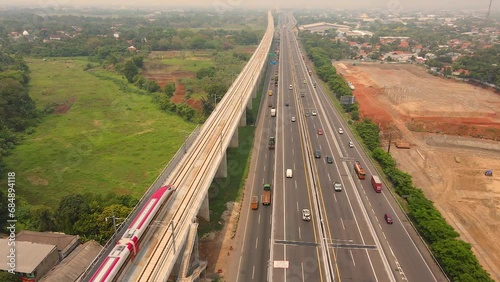 High Speed Indonesia Railway named Whoosh speeding fast beside the toll road. Aerial view of Jakarta–Bandung High-Speed Railway.
