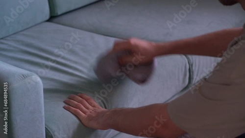 worker with yellow microfiber rag cleaning sofa textile at home