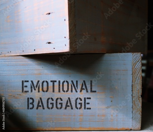 Wood boxes with text written EMOTIONAL BAGGAGE  - concept of carrying all disappointments, wrongs and trauma of the past in a heavy load, negative, unprocessed emotions from past experiences