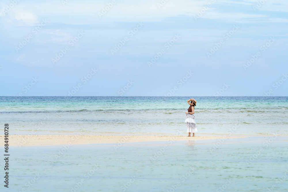 Single tourist asian woman in white dress stand by the sea on summer season, enjoy on beach relaxed, happy and freedom on vacation. Phi Phi Island, Krabi, Thailand. Leave free space for text input.