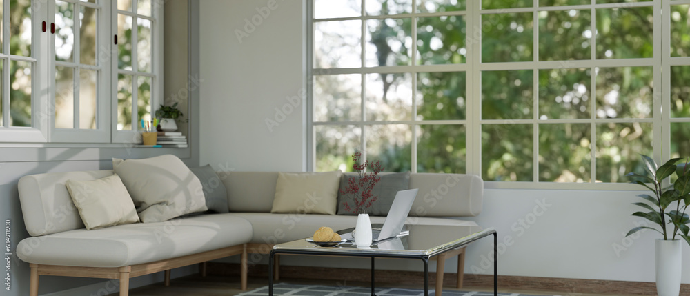 A modern and comfortable living room with a corner couch, a coffee table, a houseplant, and windows. A modern and comfortable living room with a corner couch, a coffee table, a houseplant, and windows.