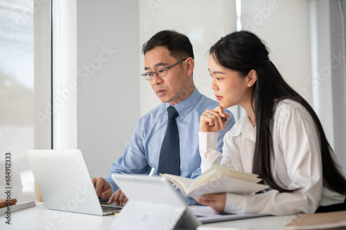 Young motivated businesswoman working with experience senior businessman in the white modern office room.
