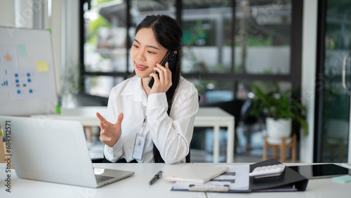 Businesswoman having a phone call with her customer while working in the office room.