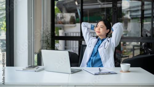 Foto A carefree doctor is putting her hands behind her head, taking a break after work at her desk