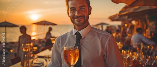 At dusk, a formal-dressed waiter offers champagne on the beach.. photo