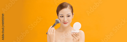 Young woman applies powder on the face using makeup brush. web banner.