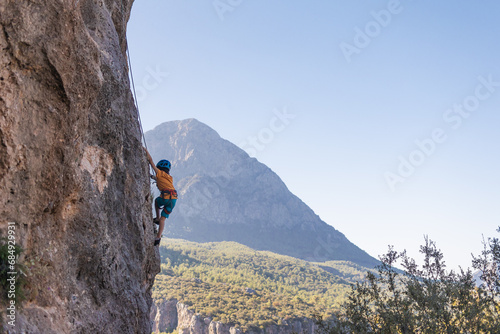 Child rock climber. The boy climbs the rock. The child is engaged in rock climbing on natural terrain. Sports kid spends time actively.