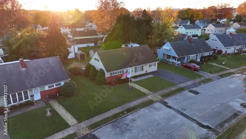 Suburban neighborhood with single-family homes and an American flag at sunset. Aerial shot during golden hour. Push in. photo