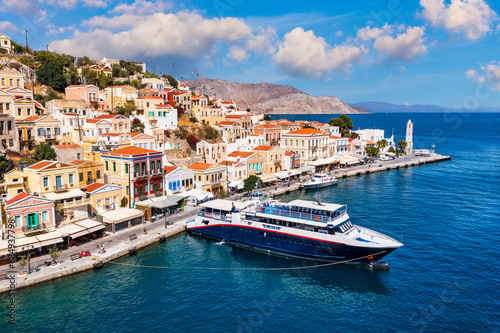 View on Symi (Simi) island harbor port, classical ship yachts, houses on island hills, Aegean Sea bay. Greece islands holidays vacation travel tours from Rhodos island. Symi, Greece, Dodecanese.