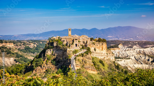 The famous Civita di Bagnoregio on a sunny day. Province of Viterbo, Lazio, Italy. Medieval town on the mountain, Civita di Bagnoregio, popular touristic stop at Tuscany, Italy. photo