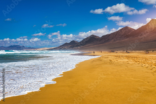 Amazing Cofete beach with endless horizon. Volcanic hills in the background and Atlantic Ocean. Cofete beach, Fuerteventura, Canary Islands, Spain. Playa de Cofete, Fuerteventura, Canary Islands.