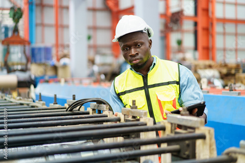 American - African worker inspecting machine in factory, machanical engineer working on machines in factory. photo