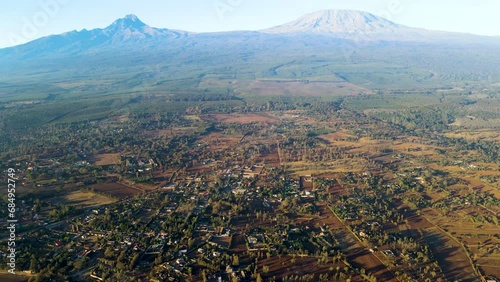 Sunrise- Kenya landscape with a village, Kilimanjaro and Amboseli national park - tracking, drone aerial view. skyline of Loitokitok in background during sunny day. Two class society in Africa.