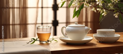 At the Asian-themed breakfast table, a white porcelain teacup is filled with a healthy, organic, natural tea, brewed from medicinal plants, as a part of the Japanese and Chinese lifestyle, promoting a photo