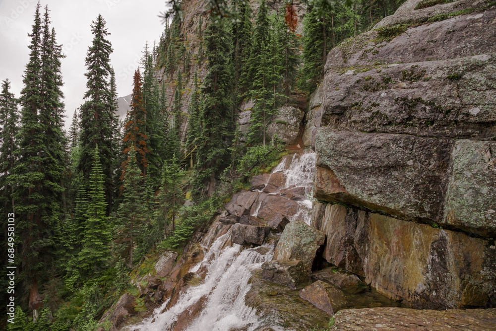 A high mountain waterfall in the middle of a coniferous forest and the slopes of the Rocky Mountains. Tourism concept, eco recreation, sustainable life. Alberta, Canada