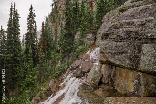 A high mountain waterfall in the middle of a coniferous forest and the slopes of the Rocky Mountains. Tourism concept, eco recreation, sustainable life. Alberta, Canada