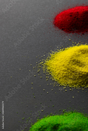 Vertical image of green, yellow and red powders with copy space on black background