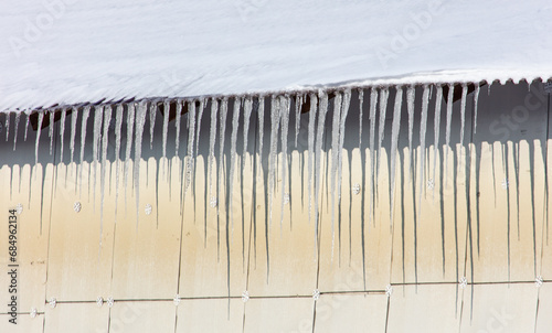 Icicles hang from the roof of the house. Winter