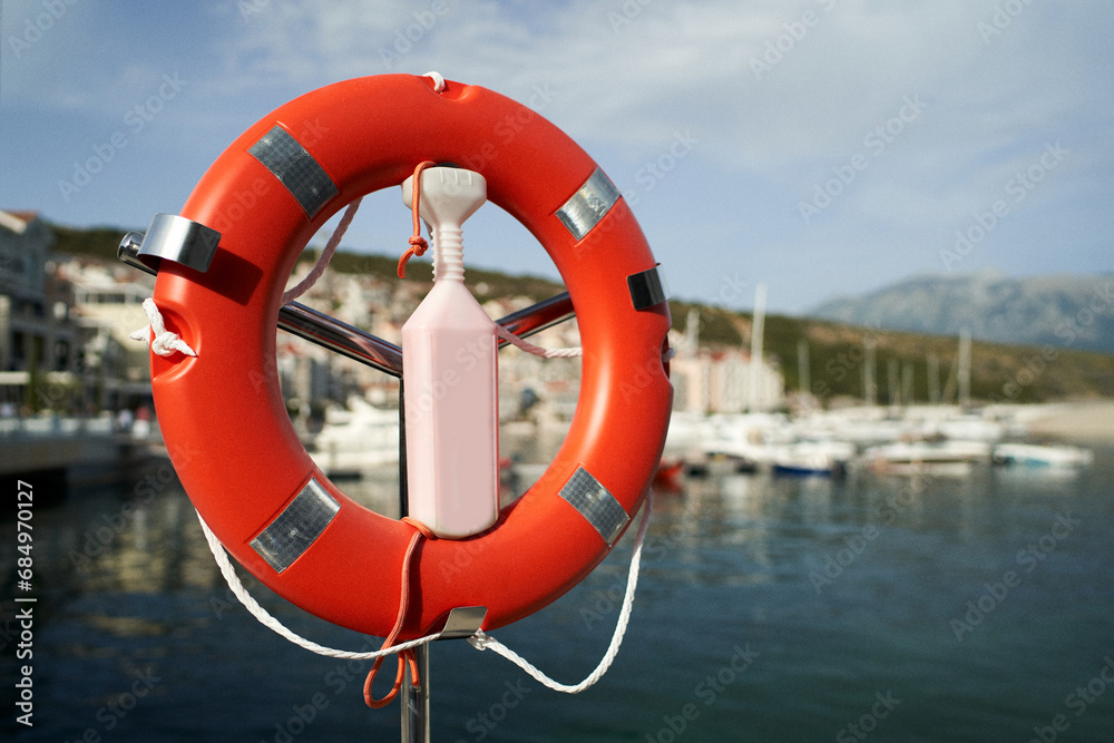 Lifebuoy on a rack with a lock at the pier against the backdrop of mountains