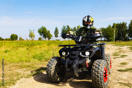 A kind of ATV in nature. Off-road driving on an all-terrain vehicle. Promotional postcard.