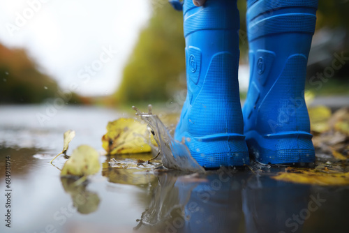 legs of child in blue rubber boots jumping in the autumn puddles © alexkich