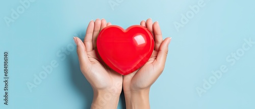 Red heart in hand with blue background