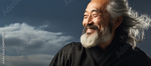 In a portrait of an old Countryn man, his face radiates happiness as he stands isolated against a white background, showcasing his fashionable black summer attire, while clouds linger in the sky above photo