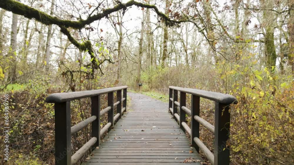 Gimbal shot smoothly going over wooden bridge on a fall day.