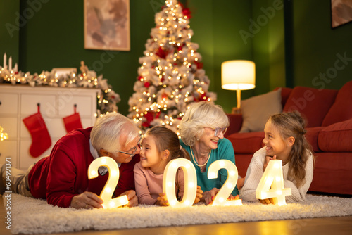 Grandchildren and grandparents holding illuminative numbers 2024 for New Year's Eve photo