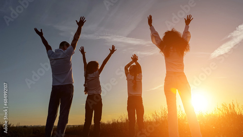 Foto Happy family raise hands up overlooking setting sun