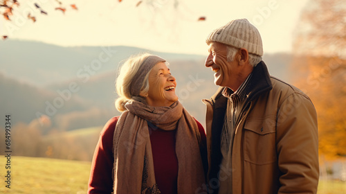 秋冬の自然の中で、高齢者の老夫婦2人が笑顔で向かい合って笑って散歩している写真 photo