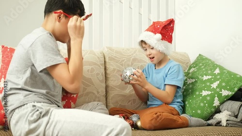 preparing for Christmas. Two brothers are sitting on the sofa in the living room with Christmas balls.