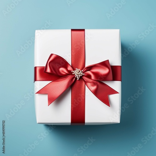 White gift box with red ribbon bow on blue background, top view