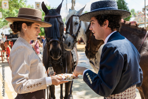 Classy happy ethnic couple drinking and eating during Horse Fair photo