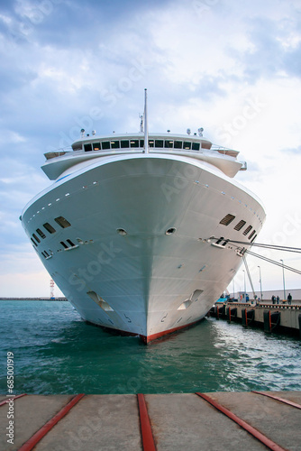 A large white cruise ship is moored in the port. A passenger ship with 11 decks awaits tourists. Cruise ship bow, front view