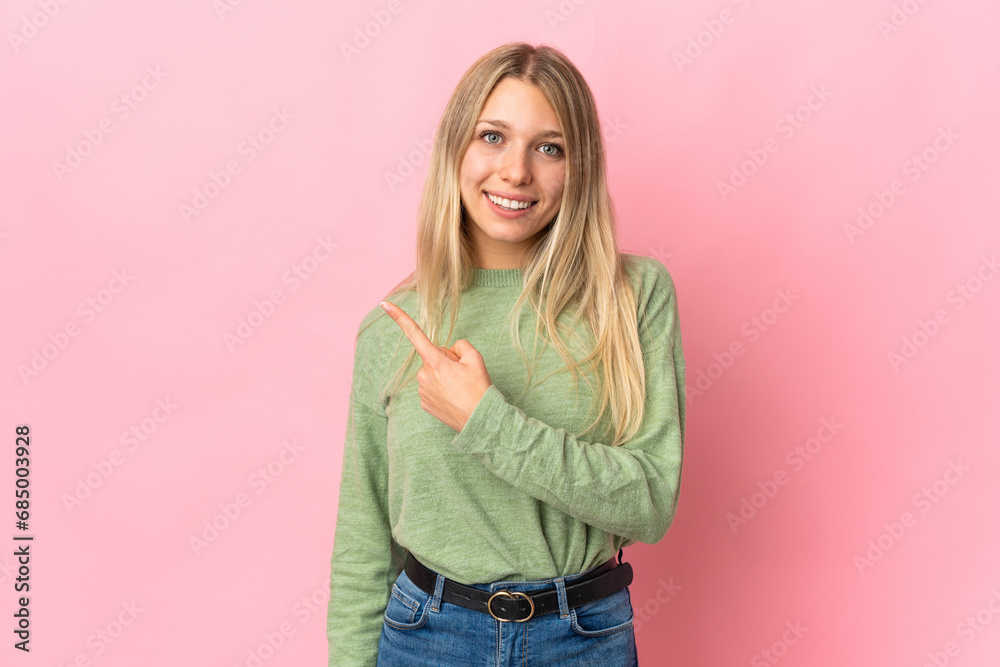 Young blonde woman isolated on pink background pointing to the side to present a product Young blonde woman isolated on pink background pointing to the side to present a product
