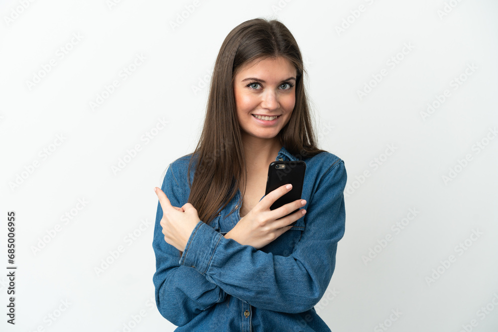 Young caucasian woman isolated on white background using mobile phone and pointing back Young caucasian woman isolated on white background using mobile phone and pointing back