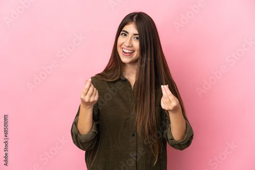 Young caucasian woman isolated on pink background making money gesture