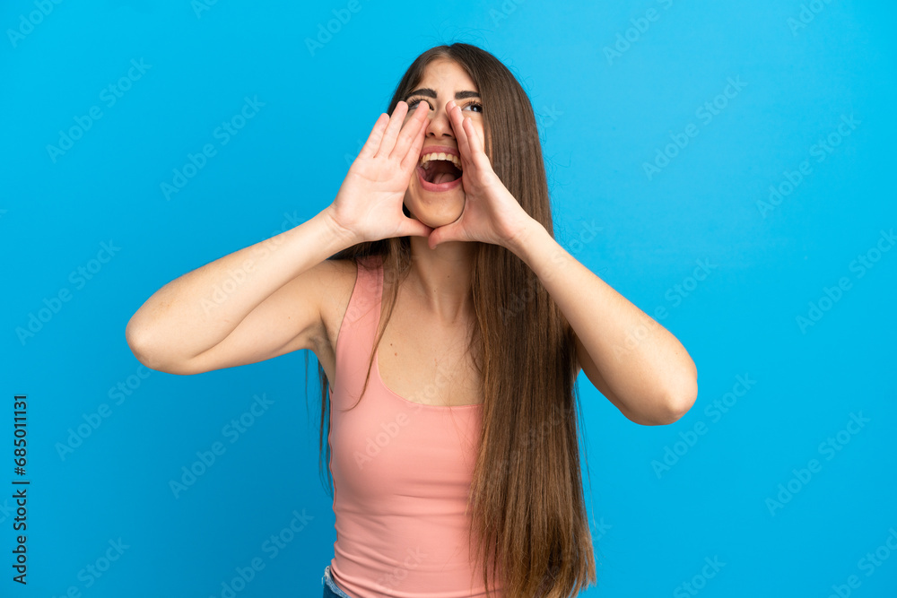 Young caucasian woman isolated on blue background shouting and announcing something Young caucasian woman isolated on blue background shouting and announcing something