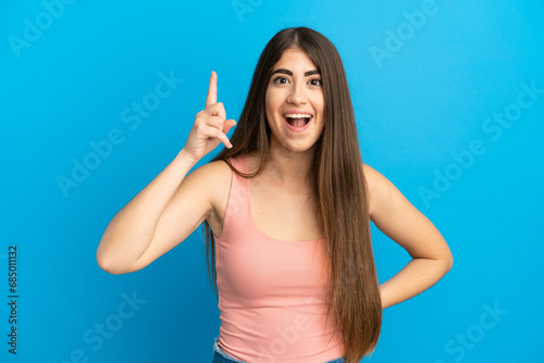 Young caucasian woman isolated on blue background intending to realizes the solution while lifting a finger up