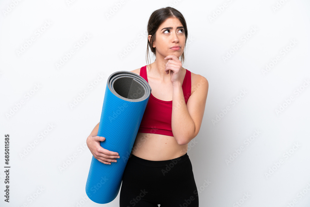 young sport woman going to yoga classes while holding a mat isolated on white background having doubts young sport woman going to yoga classes while holding a mat isolated on white background having doubts